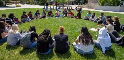 Group of students sitting in a circle on the grass at orientation