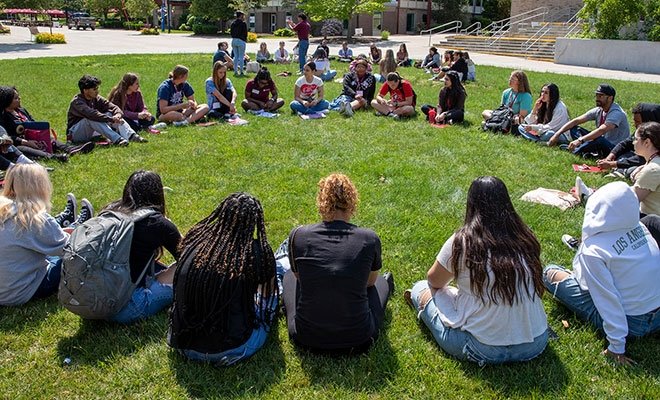 Group of students sitting in a circle on the grass at orientation