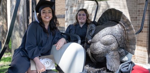 Class President and Secretary sit on golf cart with 2024 Class Gift --Geráld the Turkey