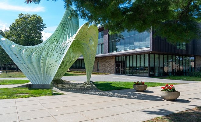 Large sculpture in front of modern campus building