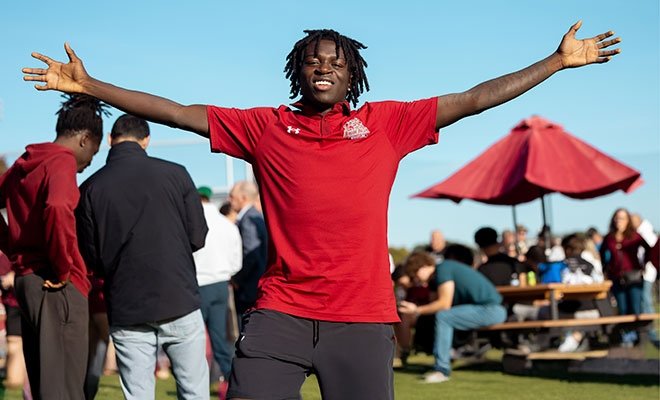 Student athlete reaching up joyfully among a crowd