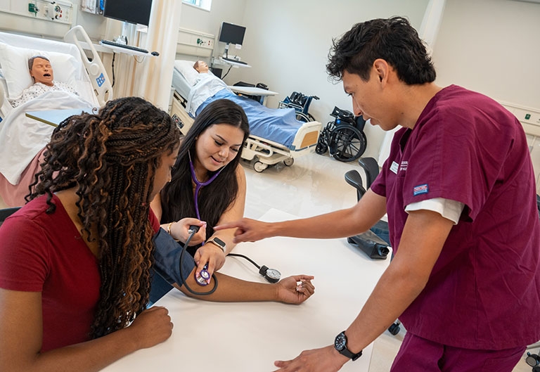 Nursing student taking a person's blood pressure in a simulation room