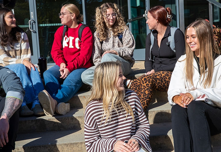 Students sitting on outside steps, talking