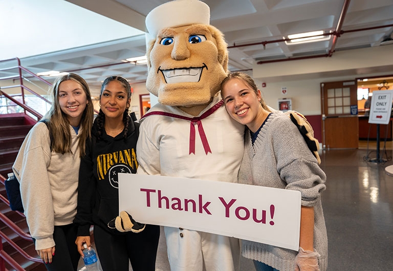 Happy students posing with the anchorman and a thank you sign