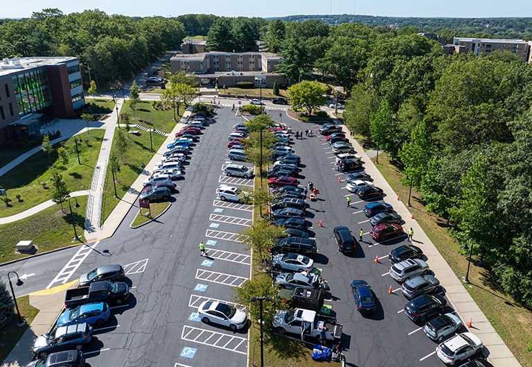 Lots of cars parked and driving into lots near dorms and Feinstein building