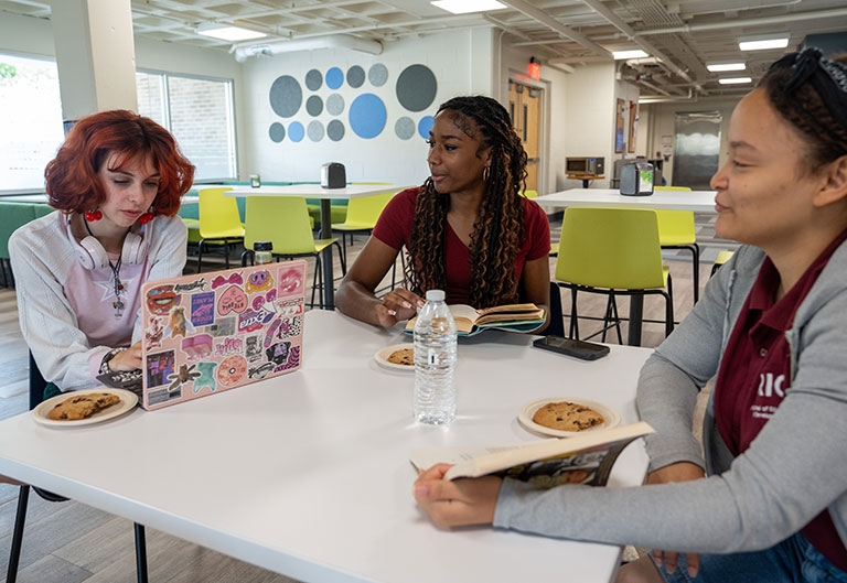 Students working and eating at a table at the Beestro