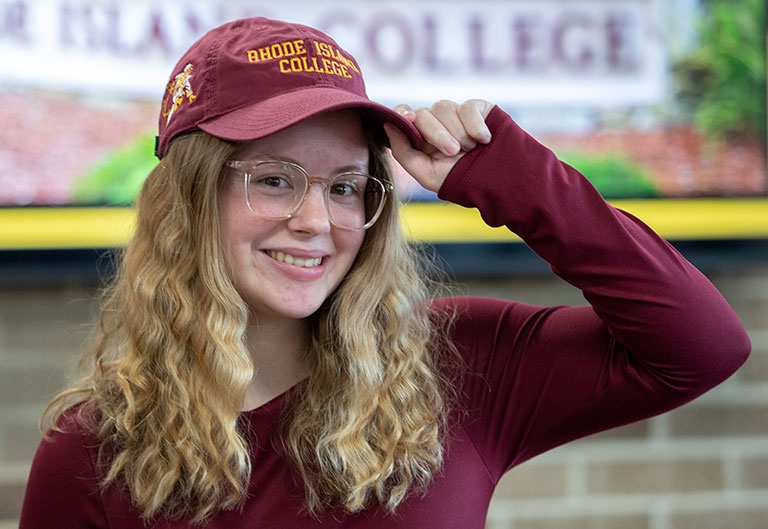 Student smiling, putting on RIC baseball cap