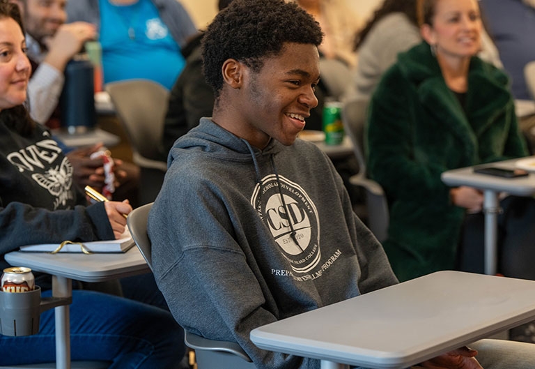 Students smiling, at desks in classroom