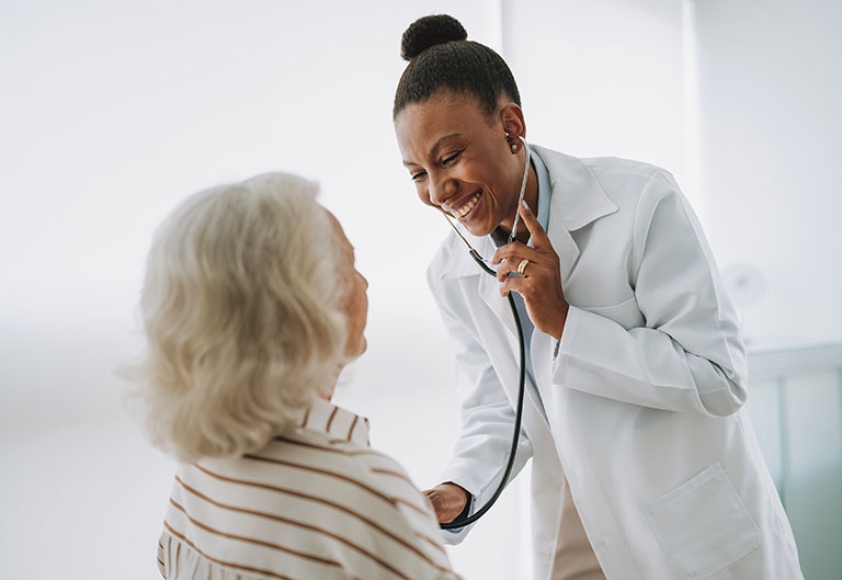 Doctor or nurse smiling, listening to older patient's breathing