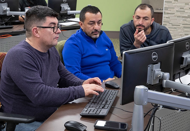 Three students working on computers at the Workforce Development Hub