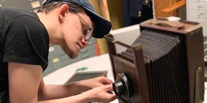 RIC alum Antonio Santurri '18 tinkers with a vintage camera at Providence City Archives
