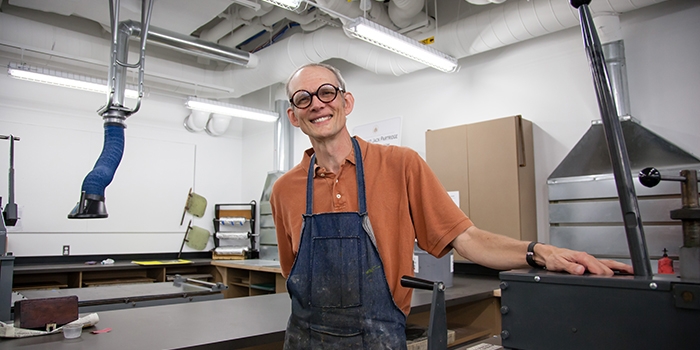 ​​Professor of Art Stephen Fisher poses in RIC's Alex and Ani Hall's printmaking studio.