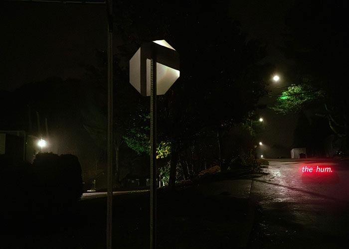 “The Hum,” photograph by Simone Emerich of a dark street with a neon "the hum" sign
