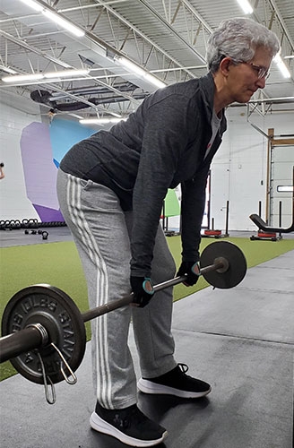 Elderly woman lifts barbells in gym