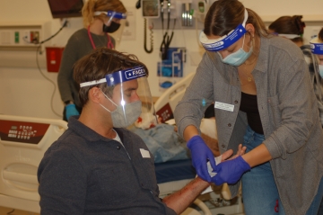 A nursing student bandages a crisis actor's fake injury during a disaster simulation exercise
