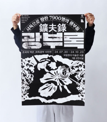 Person holding up a black-and-white poster with Korean text