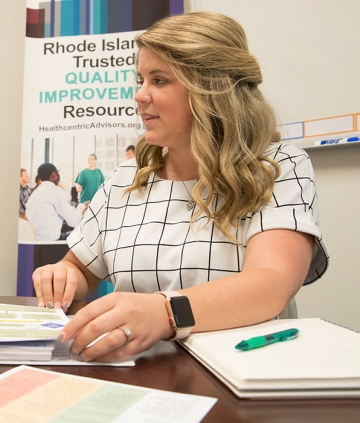 Healthcare administration student working with materials on a table and behind her.