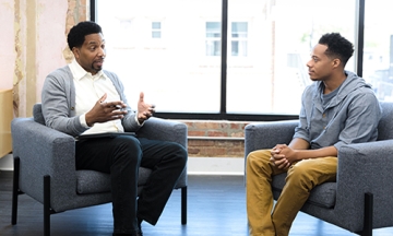 Black male mentor sitting talking with black student