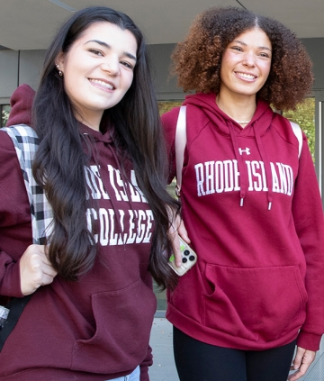 Two students posing in RIC sweatshirts, outside on campus