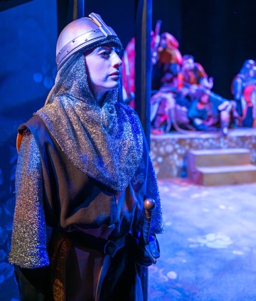 Theatre student in knight costume on stage, during performance