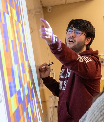 Math student pointing at a bright, multicolored projection