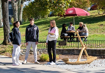 Students near anchor and sitting under table with umbrella