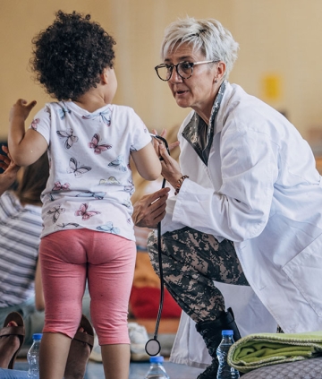 Medical professional with stethoscope helping young child