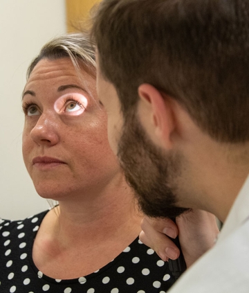 Nursing student looking into patient's eyes with light