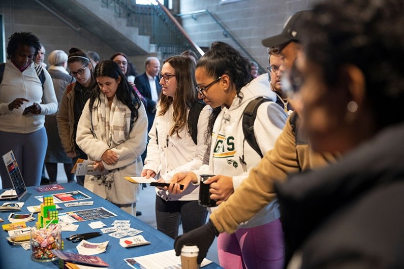 Students gather at a materials table at the launch of the Institute for Cybersecurity & Emerging Technologies