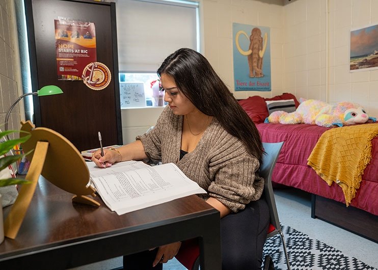 Student writing at dorm room desk