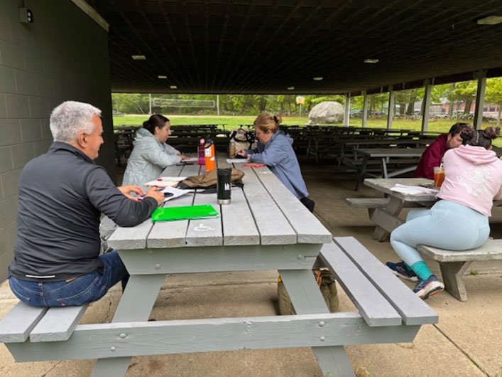 Rhode Island Writing Project event attendees writing outdoors at picnic benches