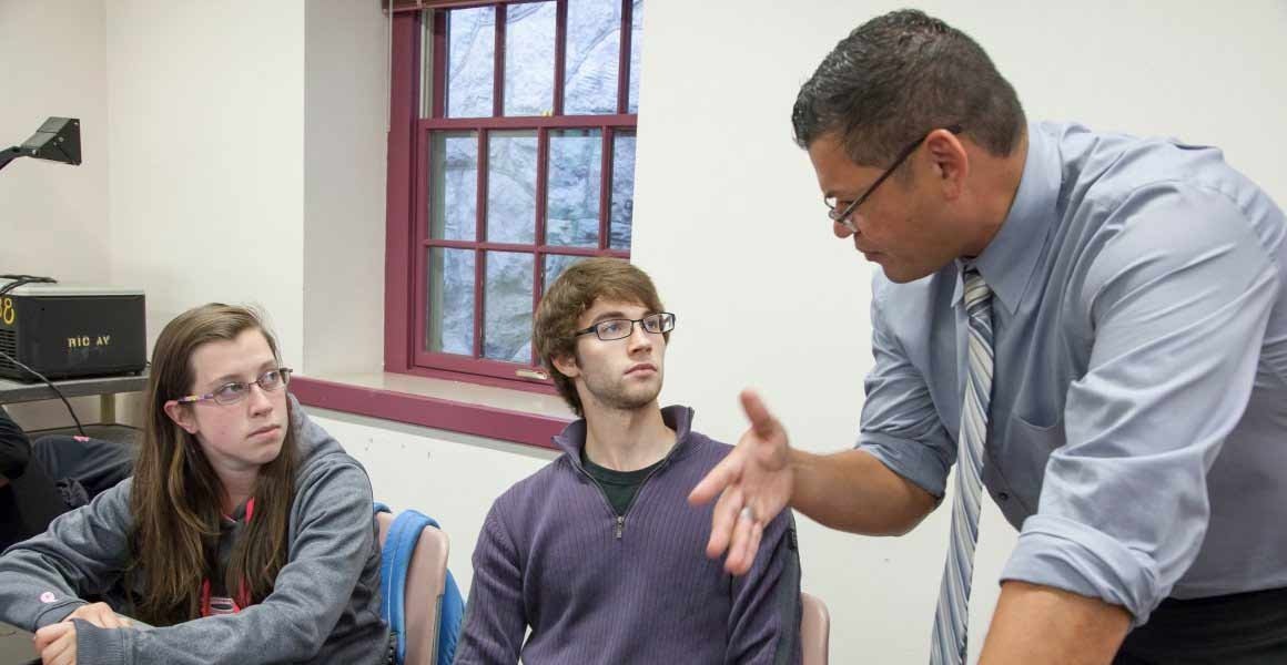 adjunct faculty taking to two students in a classroom
