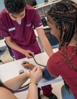 Nursing students taking patient's blood pressure