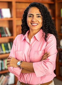 Latina professor standing in front of bookshelves