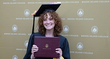 Graduate student in cap and gown, holding diploma