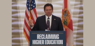 Florida Governor Ron DeSantis standing at podium with sign Reclaiming Higher Education