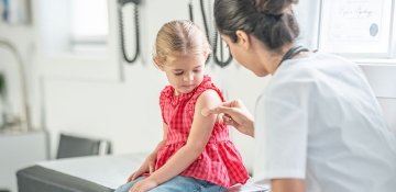 Nurse applying bandaid on young child