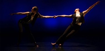 Two dancers dancing together dramatically in spotlight