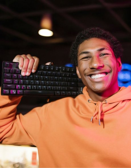 High school student holding computer keyboard on his shoulder and smiling