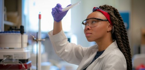 Female looking closely at item in science lab