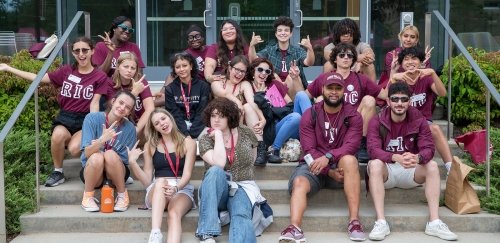 Group of students at orientation sitting together, excited, outside on steps