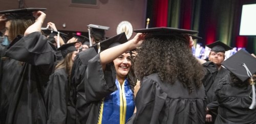 Students at cap & gown convocation capping each other