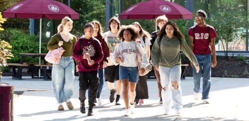 Students walking on campus together in RIC gear, in the sun