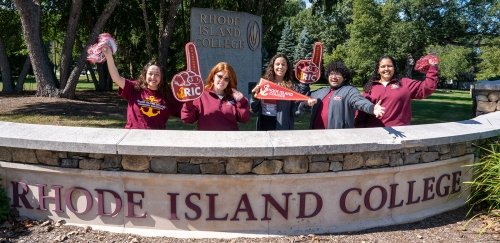 Admissions Counselors showing their RIC pride by campus main entrance