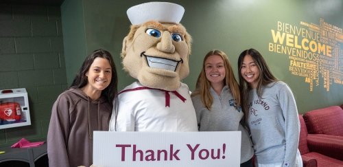 Anchorman with students and thank you sign
