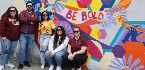 Group of students posing by the Be Bold colorful mural