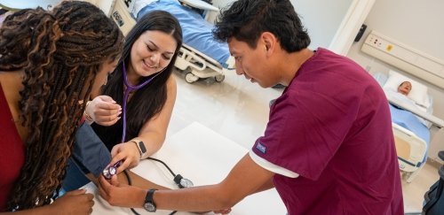 Students taking patient blood pressure in nursing simulation room