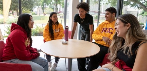 Students in RIC gear talking around a table