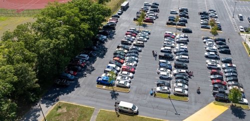 Drone shot of campus parking lot with cars and people