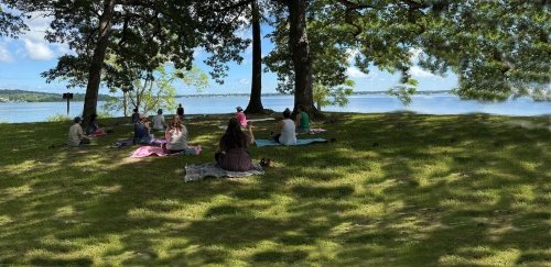 Rhode Island Writing Project event attendees, sitting in group, on blankets, by the water